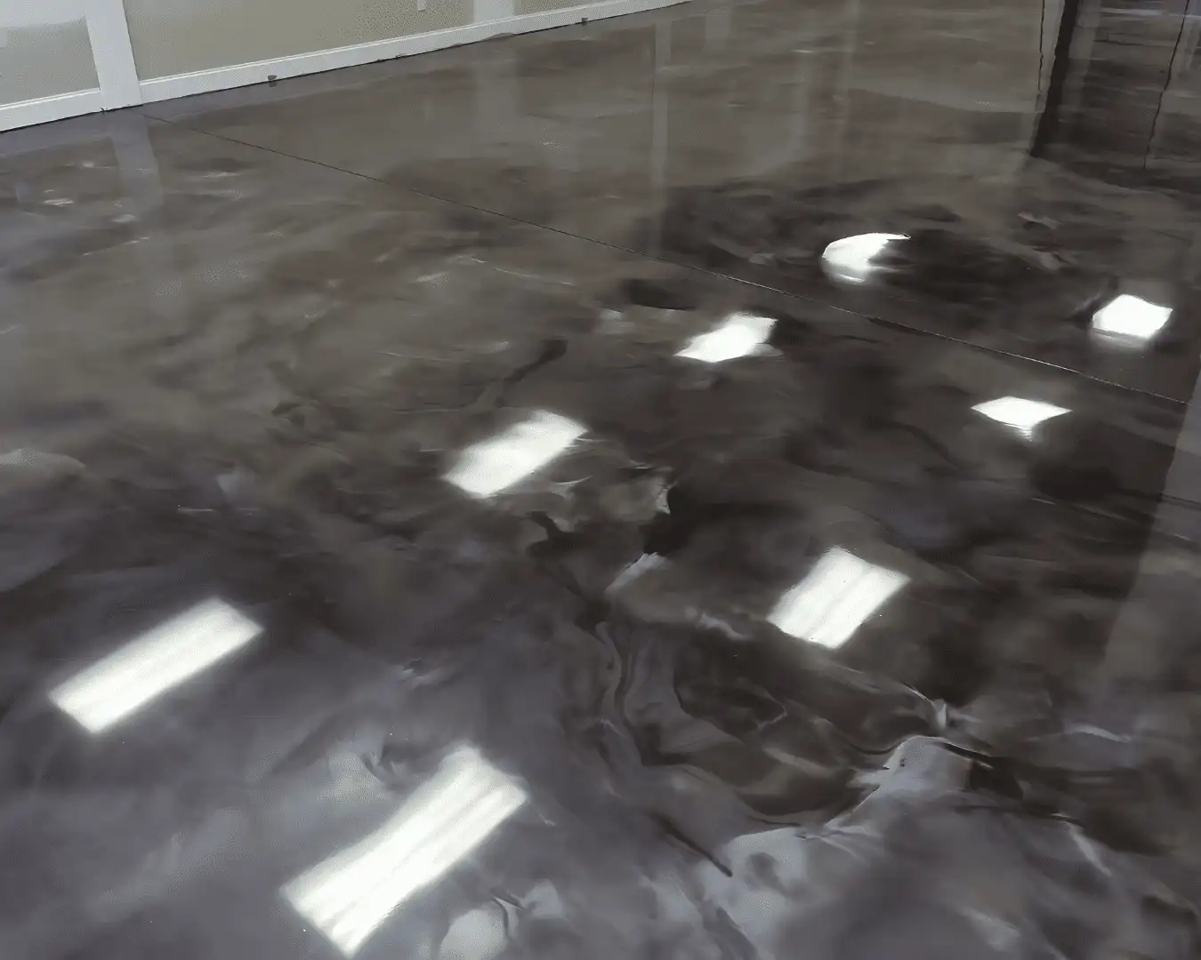 Deep charcoal metallic epoxy floor with flowing molten-stone effect installed in an Eastern Washington showroom