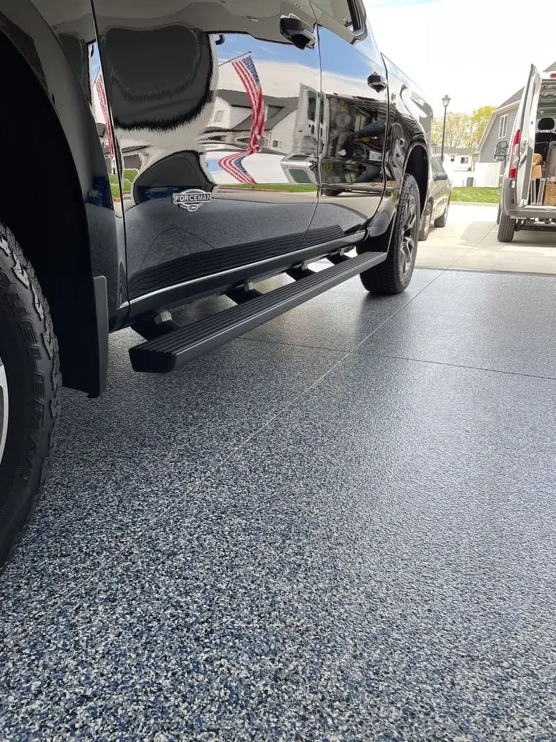 Repaired and coated garage floor with a vehicle parked over decorative flake epoxy