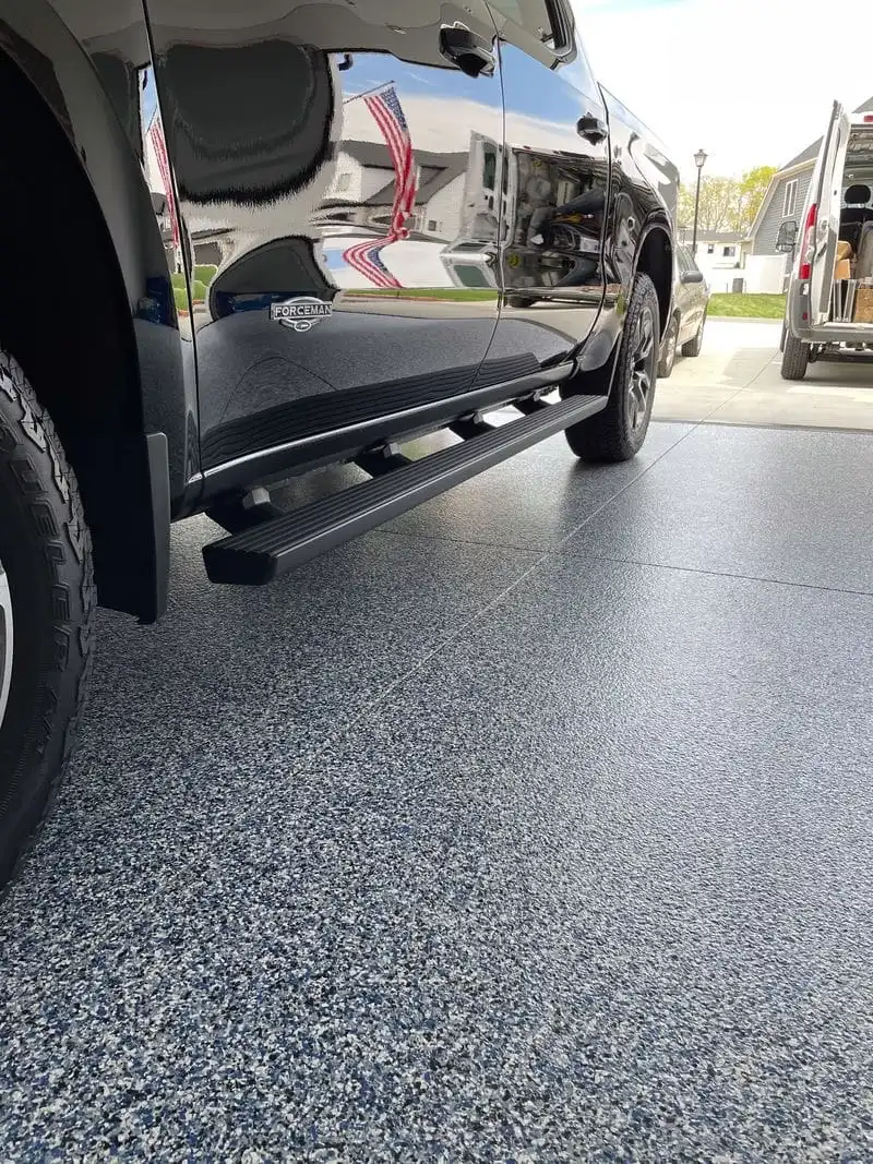Repaired and coated garage floor with a vehicle parked over decorative flake epoxy