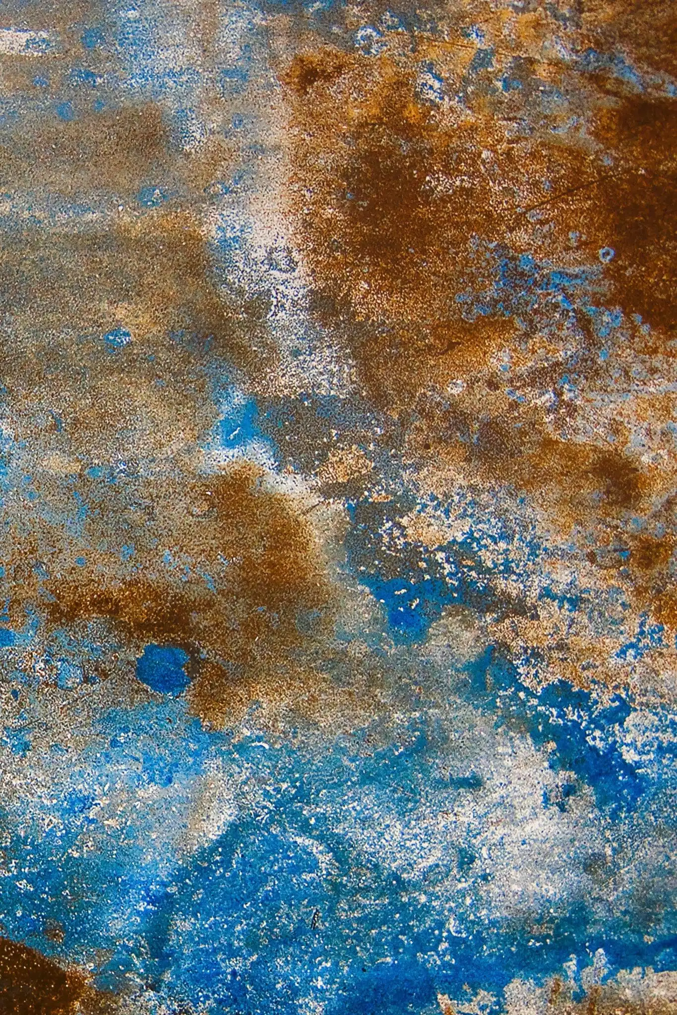 Acid-stained concrete with rich rust and blue variegated tones, a permanent stone-like finish